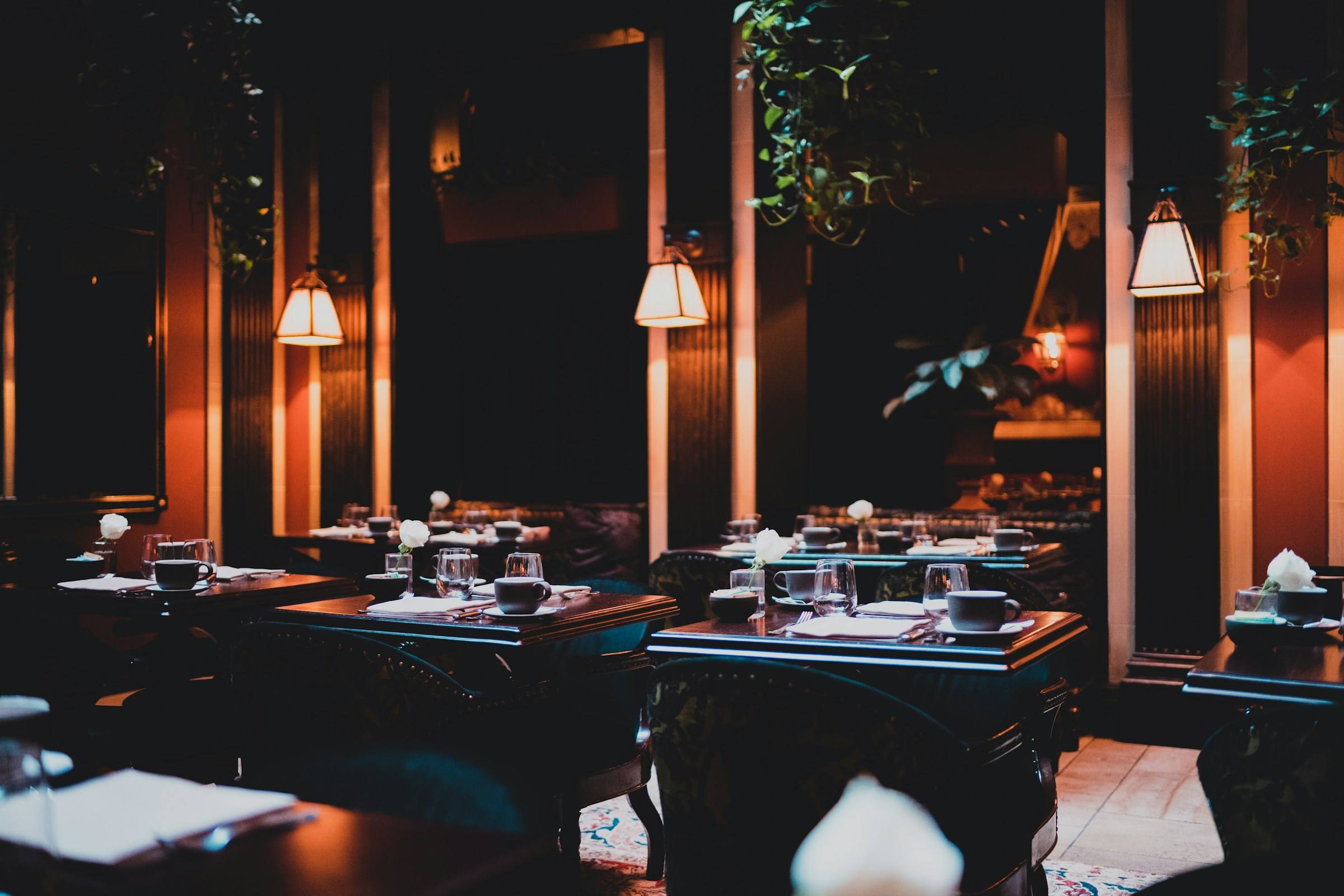 A dimly lit dining room with warm pendant lights